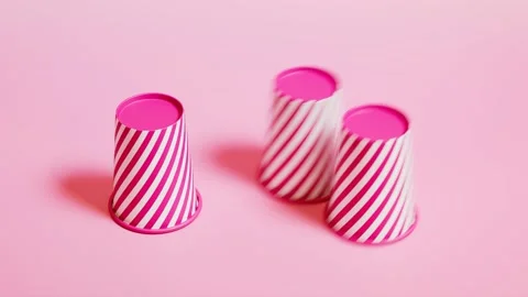 3 Cups and a ball game. Try to guess where a ball is. Pink background. Side view Stock Footage 201172262