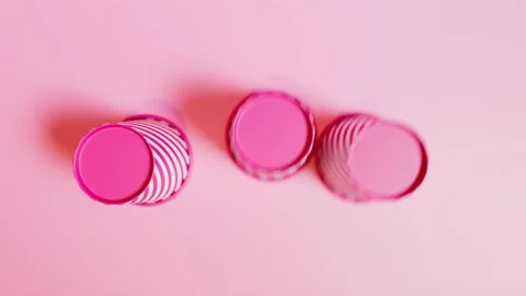 3 Cups and a ball game. Try to guess where a ball is. Pink background. Top view Stock Footage 201172289