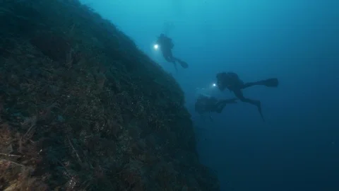 3 diver approaching to a rock formation, Giannutri, Mediterranean sea, Italy Stock Footage 108176891
