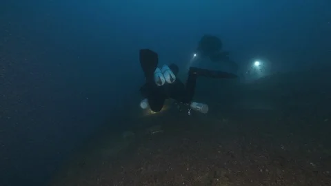3 diver lights up the seabed searching the shipwreck Nasim, Giannutri, Italy Stock Footage 108166998