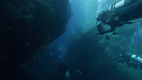 3 divers swim in groove between rocks, Ustica, Sicily, Mediterranean sea Stock Footage 125105061