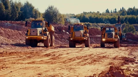 3 dump trucks driving out of red clay quarry. Vidéo 236960231
