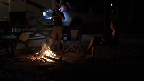 3 Friends Hang Out Around Fire in Front of 5th Wheel Camper Stock Footage