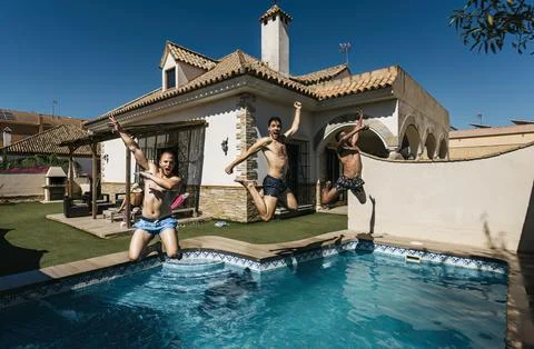 3 friends jumping into a pool doing a pirouette Stock Photos