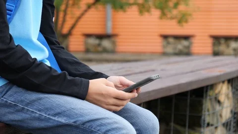3 Kid boy alone sit on a bench by a school building use type watch his smart  Stock Footage 94613185