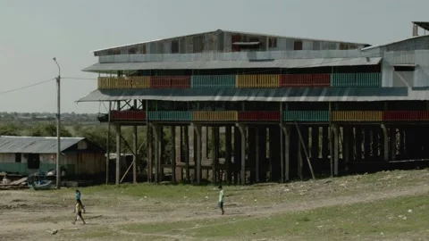 3 kids passing by a typical stilt building in Iquitos, Peru Stock Footage 188912098