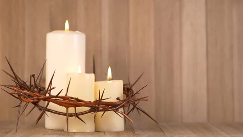 3 Lit Candles surrounded by Crown of Thorns on the left on the frame. Communion Stock-Footage 128713553