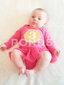 3 Month Old Cute Baby Girl, Infant in Hot Pink tu-tu, lying on the white bed, Ne Stock Photos