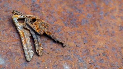 3 old rusty keys on ring shot on steel textured background. Copy space. Stock Photos