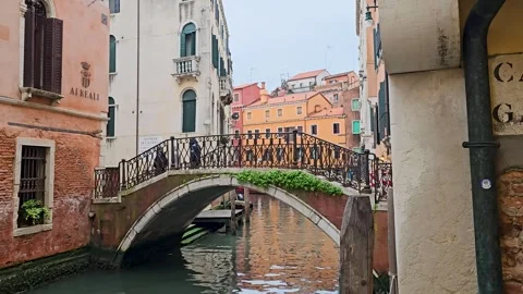 3 people cross small bridge over narrow canal-Venice-Rainy day Stock Footage 281697936