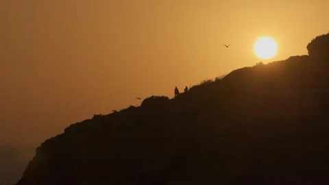 3 People stroll during a sunset on a cliff in the town of Faro, Portugal. Video stock 256780788