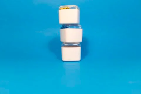 3 plastic white boxes in a row. There are colored paper clips inside. Stock Photos