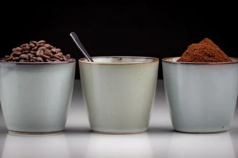 3 rustic coffee cups with coffee grounds, coffee, and ground coffee. Black ba 写真素材