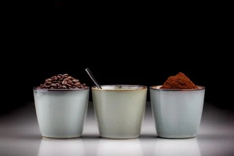 3 rustic coffee cups with coffee grounds, coffee, and ground coffee. Black ba Stock Photos