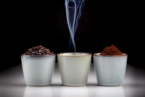 3 rustic coffee cups with coffee grounds, smoking coffee, and ground coffee. Foto stock