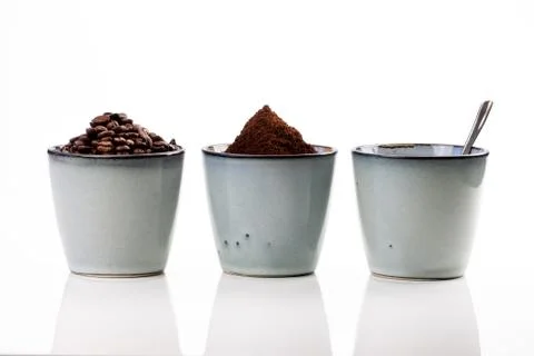 3 rustic coffee cups filled with hot coffee, beans, and ground coffee. White Foto stock