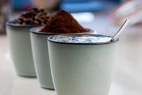 3 rustic coffee cups filled with hot coffee, beans, and ground coffee. White Stock Photos