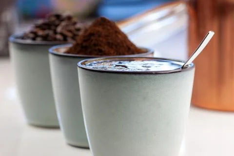 3 rustic coffee cups filled with hot coffee, beans, and ground coffee. White 写真素材