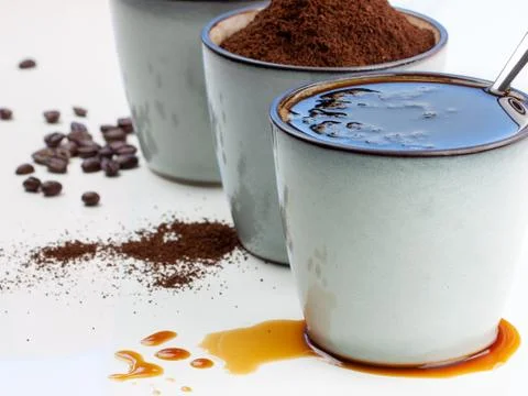 3 rustic coffee cups filled with hot coffee, beans, and ground coffee. White Stock Photos