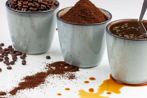 3 rustic coffee cups filled with hot coffee, beans, and ground coffee. White Foto stock