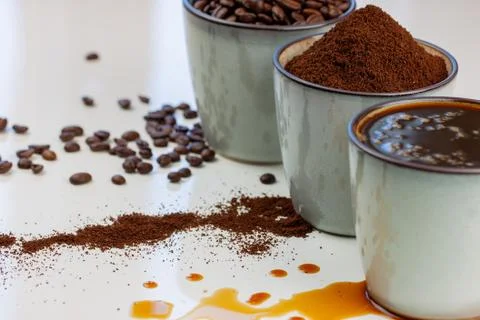 3 rustic coffee cups filled with hot coffee, beans, and ground coffee. White Stock Photos