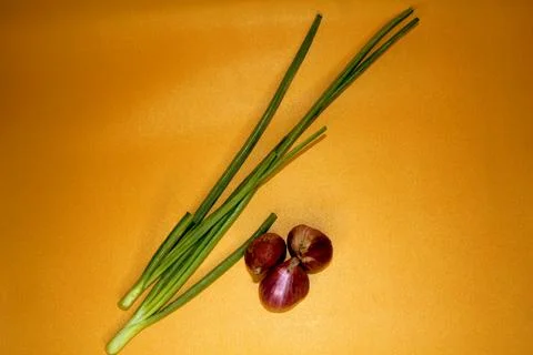 3 shallots and 2 spring onions on orange background. Stock Photos