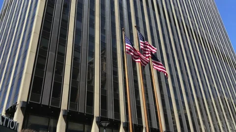 3 USA Flags Dwarfed By Imposing Office Building Stock Footage 168334150