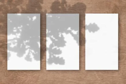 3 vertical sheets of textured white paper on wooden table background. Mockup  Illustrazione stock