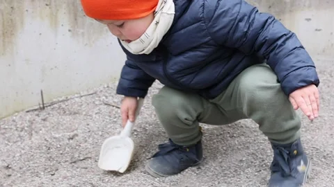 3 year boy plays with scoop and toy car outside Stock Footage 152769043