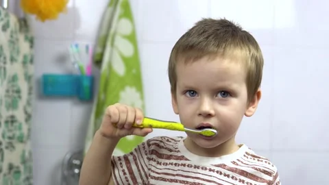 3 year old boy brushes his teeth with a toothbrush while looking at the camera Stockbeeldmateriaal 147540242