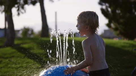 3 year old boy leans in to drink from water feature at community splash pad 스톡 동영상 233944026