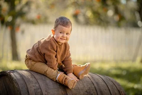 A 3-year-old boy sits on a large wooden barrel Stock Photos