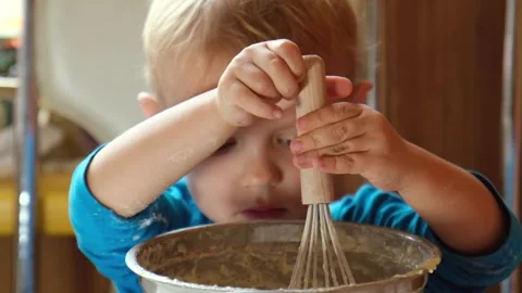 A 3-year-old boy is whisking pancake batter. The child is cooking. Stock Footage 331347460