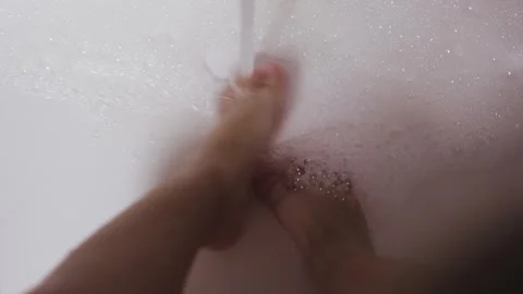 A 3-year-old child sits in the sink and washes her feet, water from the tap Stock Footage 311246853