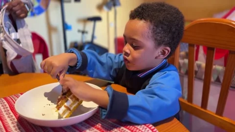 3-year-old exotic and cute black child eating a piece of carrot cake at Stock Footage 259428779