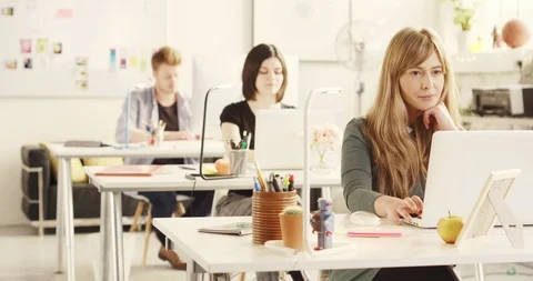 3 Young adults working in sunny casual startup office - focus on front woman Stock Footage 92190853