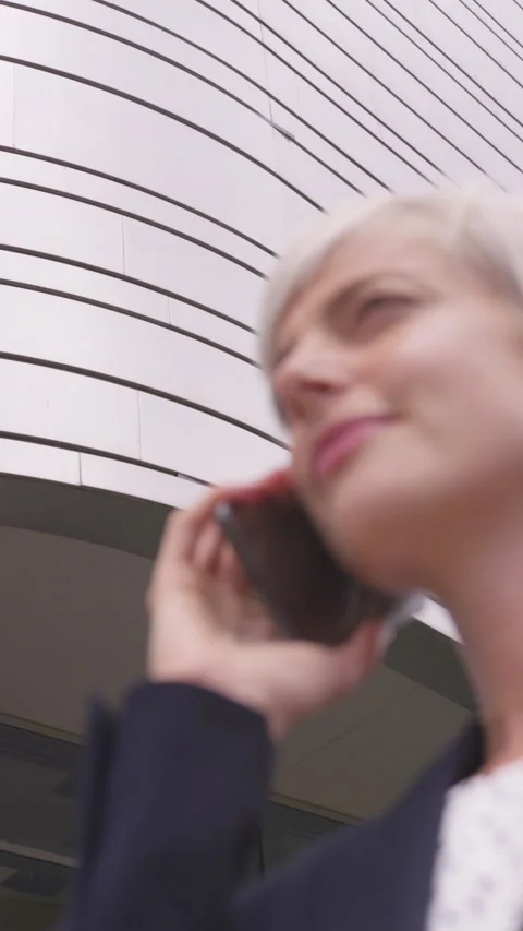 30  Something Woman with Short Pixie Talking on Cell Phone Next to Building Stock Footage 208778502