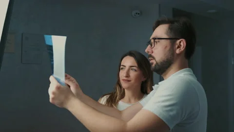 30-year-old dentist man standing talking to brunette patient on sofa and showing Stock Footage 150615000