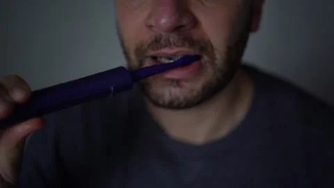 30-year-old man brushes his teeth with charcoal toothpaste using an electri.. Stock Footage 294524252
