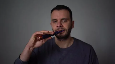 30-year-old man brushes his teeth with purple toothpaste using an electric .. Stock Footage 294524280