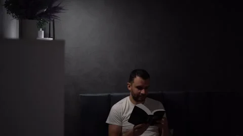 30 year old man reading bible and praying in bed with lamp light, evening r.. Stock Footage 294525085