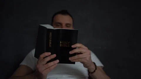 A 30-year-old man reads the Bible and prays in bed, morning routine Stock Footage 294522591