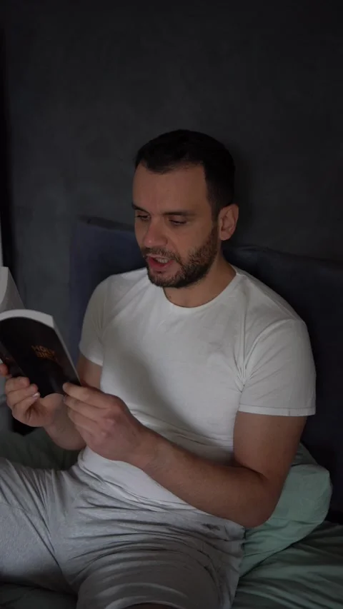 A 30-year-old man reads the Bible and prays in bed, morning routine Stock Footage 294524326
