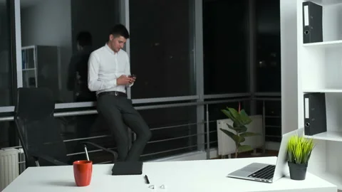 30-year-old man standing near a panoramic window in the office holding a phone Stock Footage 141142839