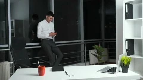 30-year-old man standing near a panoramic window in the office holding a phone Stock Footage 141671260