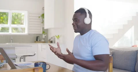 30s man joining call at kitchen, using headset, typing on laptop, gesturing with Stock Footage 348224746