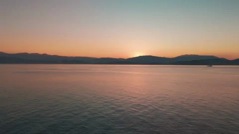 Aerial Sunrise Flight Over Calm Corfu Sea, Sun Rising Above Mainland Mountains Aerial Sunrise Flight Over Calm Corfu Sea, Sun Rising Above Mainland Mountains