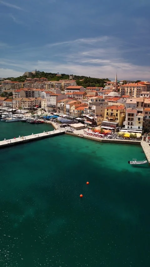 Drone Flight Towards Calvi Waterfront, Pier, Boats, and Colorful Cafes