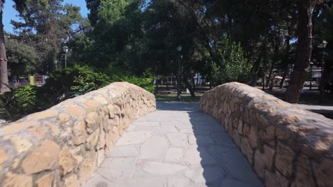 Walking Across Small Wooden Footbridge in Katerini Municipal Park, Greece