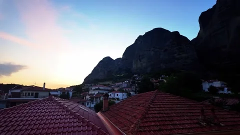 Sunset Pan Across Kalabaka Rooftops Towards Meteora Rock Giants